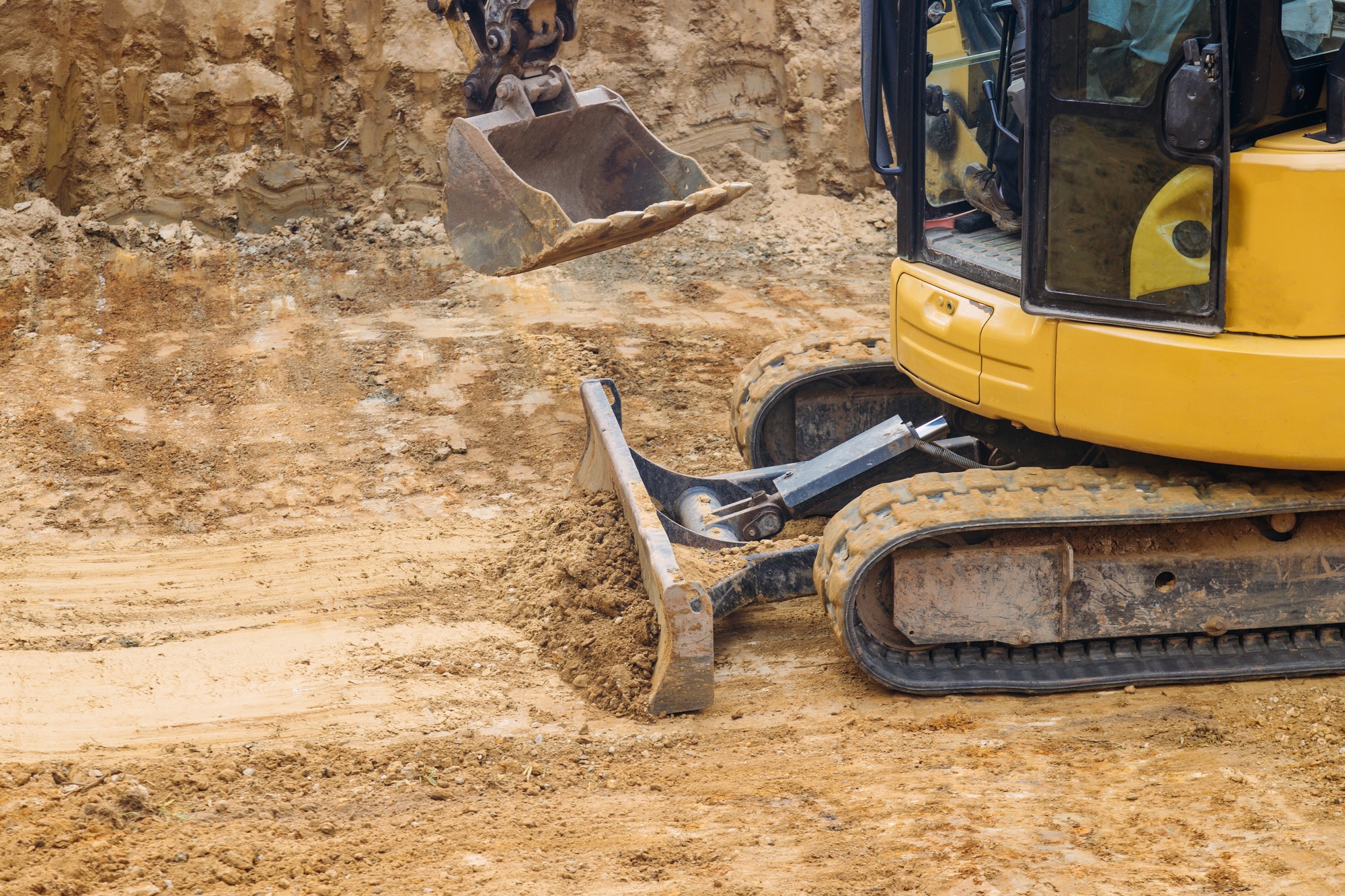Close up of bulldozer scoop moving earth in preparation for foundation building construction site,